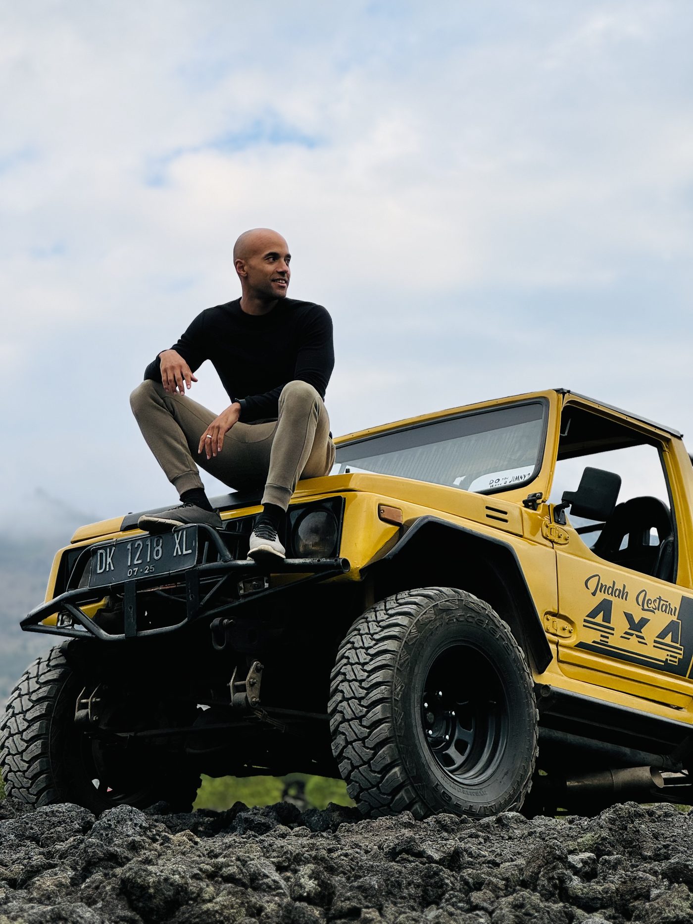 Dominik Kienzle sitzt auf der Motorhaube eines gelben 4x4-Jeeps auf Bali